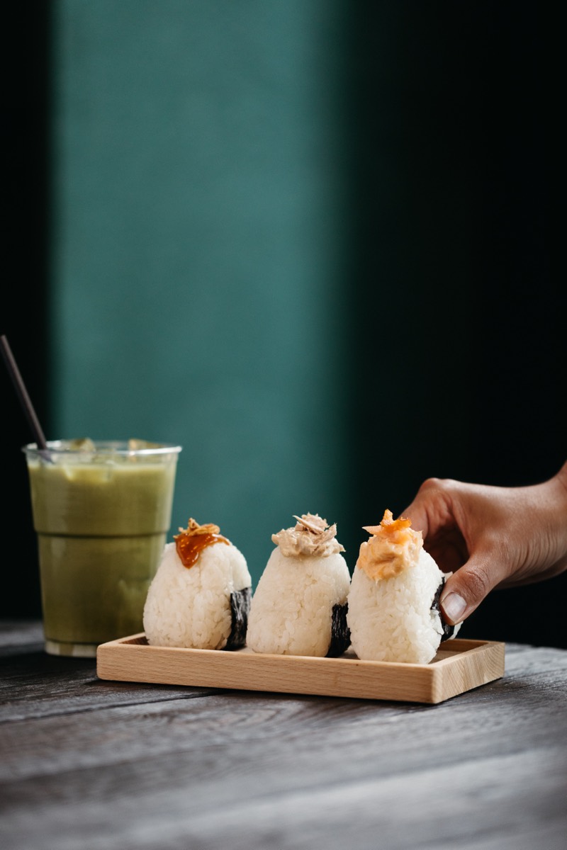 Three handmade onigiri on a wooden tray